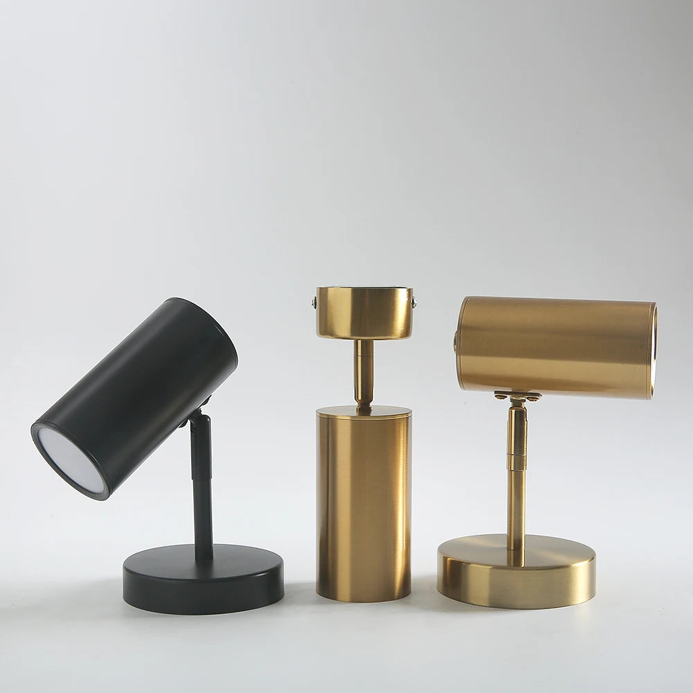 Set of three cylinder wall spotlights in matte black and brushed gold finishes, featuring adjustable heads and compact modern bases for directional lighting in contemporary interiors.