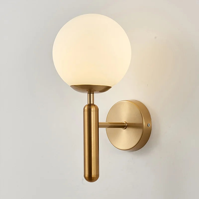 Modern wall sconce with a frosted glass globe shade and sleek gold cylindrical arm. Ideal for bedrooms, hallways, or vanity spaces with minimalist or mid-century decor style.