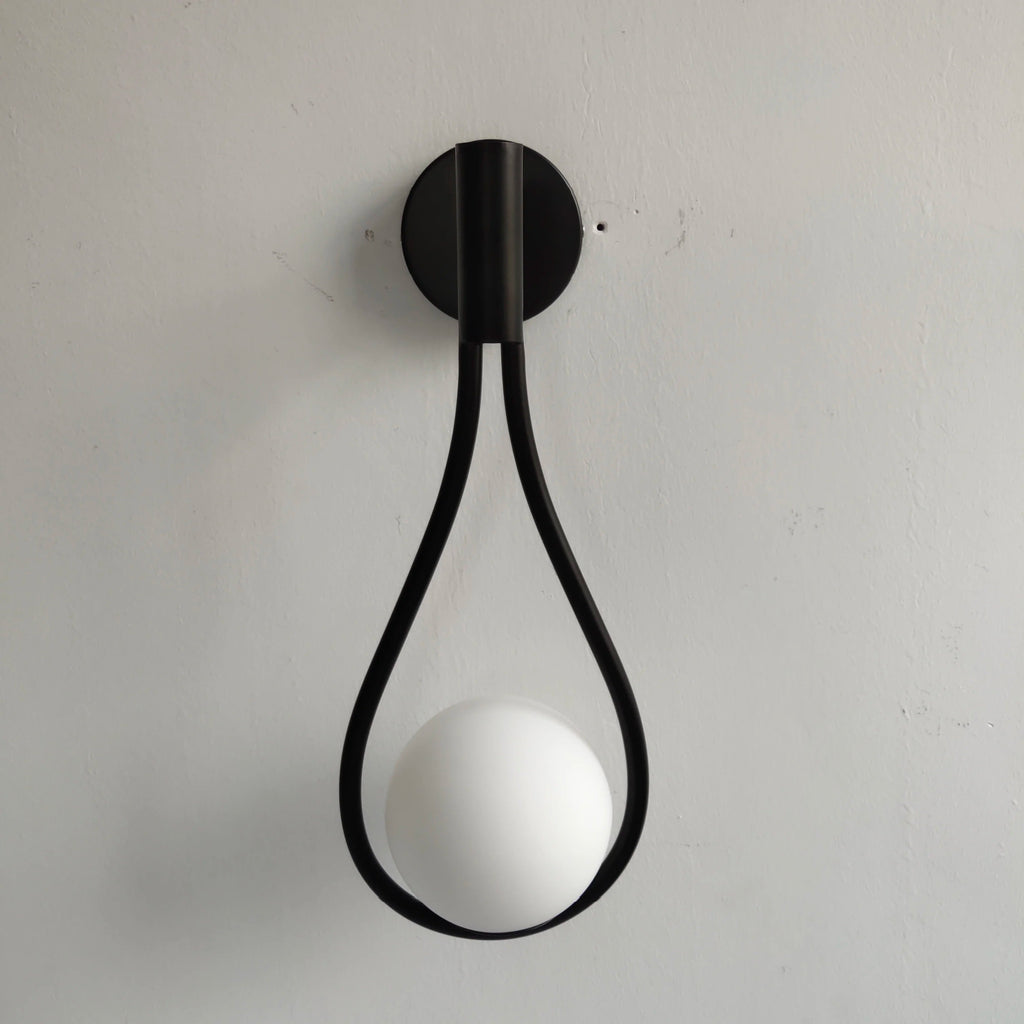 Modern bathroom wall sconce featuring a clear glass globe and sleek brass mount, perfect for contemporary bathroom or powder room lighting.