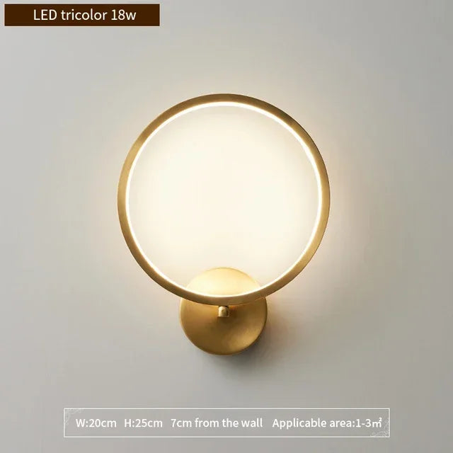 Modern round LED wall sconce in gold finish with tricolor light, 25cm height and 20cm width. Minimalist design ideal for bedrooms, hallways, or small accent lighting areas (1–3m²).