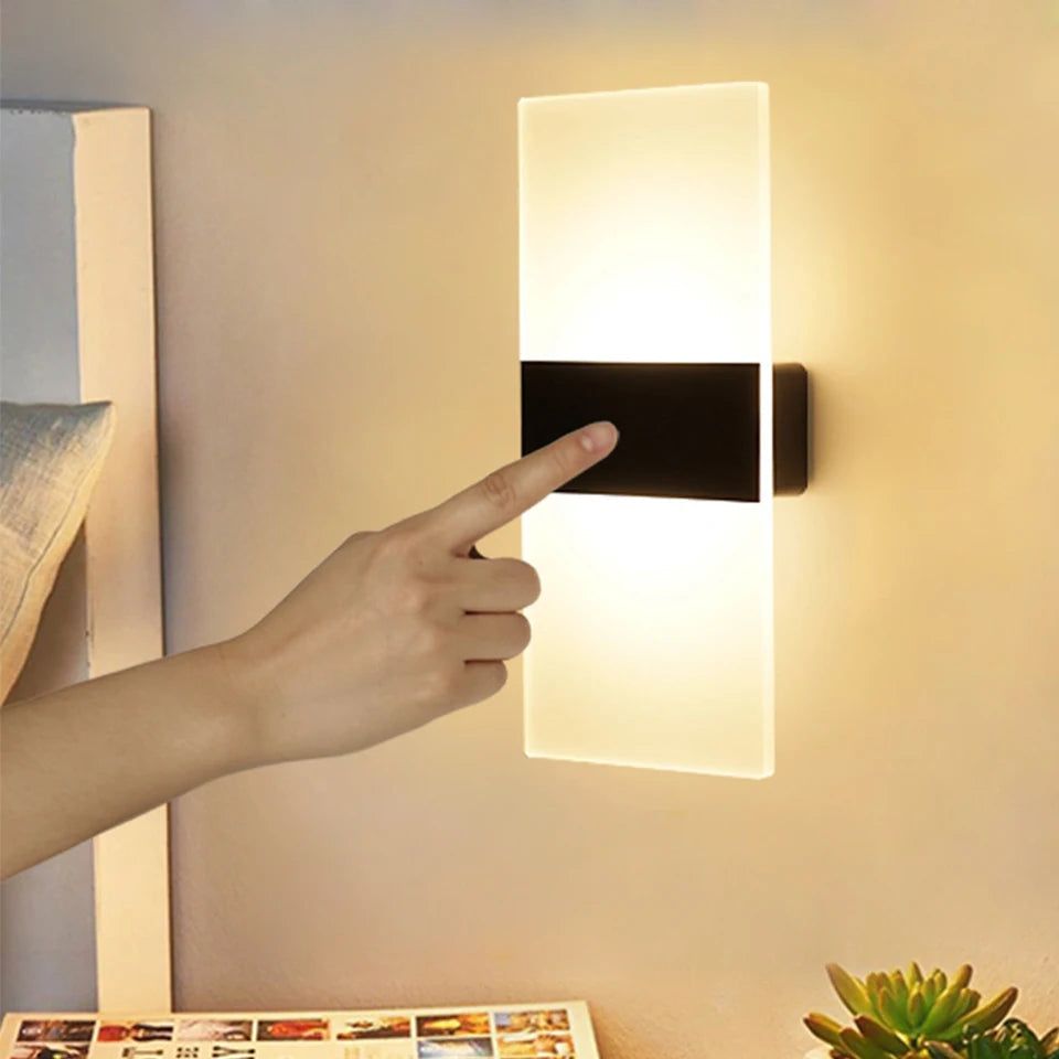Rectangular touch-activated wall sconce with frosted LED panel and matte black center accent, mounted beside a bed for ambient bedroom lighting.







