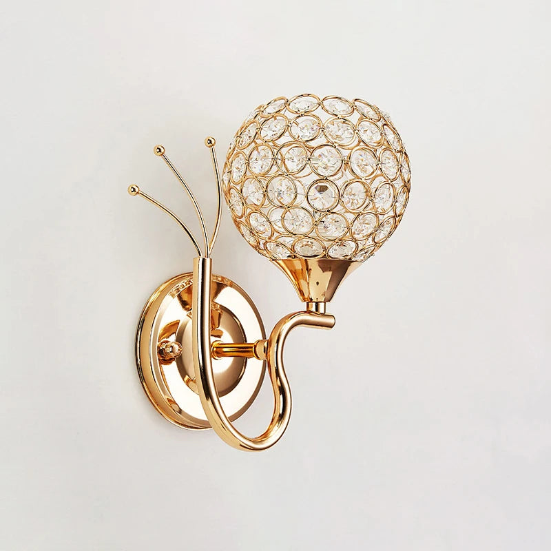 A decorative gold wall light topped with a crystal globe, creating a chic and sophisticated ambiance.