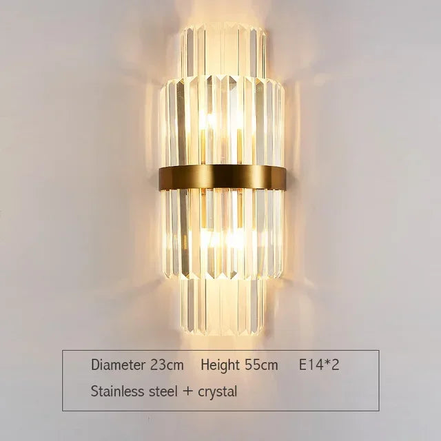 Tall crystal wall sconce with vertical glass prisms and gold central band, made of stainless steel and crystal. Measures 55cm high and 23cm wide, ideal for luxury hallway or bathroom lighting.