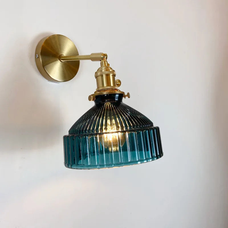 A blue glass wall light featuring a stylish brass shade, adding a modern touch to any room's decor.